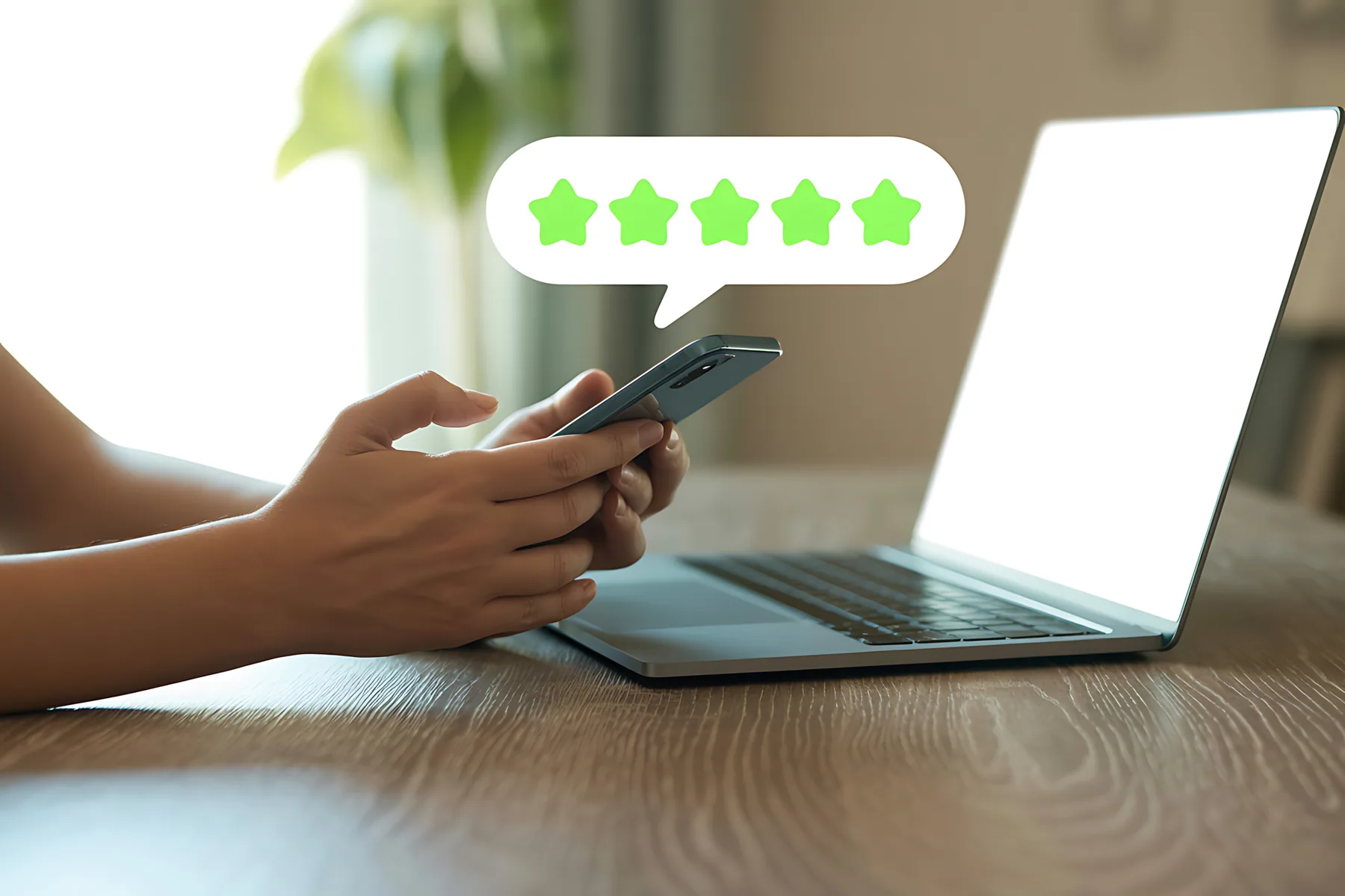 Five green stars shown on a phone held over a laptop
